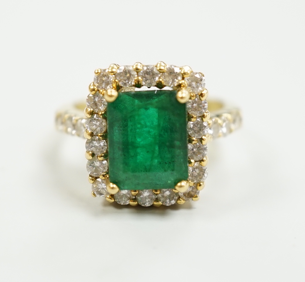 A modern 18ct gold and single stone emerald set dress ring, with diamond set border and shoulders, size L, gross weight 6.5 grams, with accompanying Beverley Hills Gemological Laboratory appraisal certificate date 18/11.